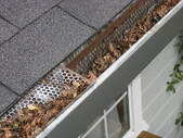 A crowded gutter is filled with leaves. Proper professional help is needed to clean the debris out.